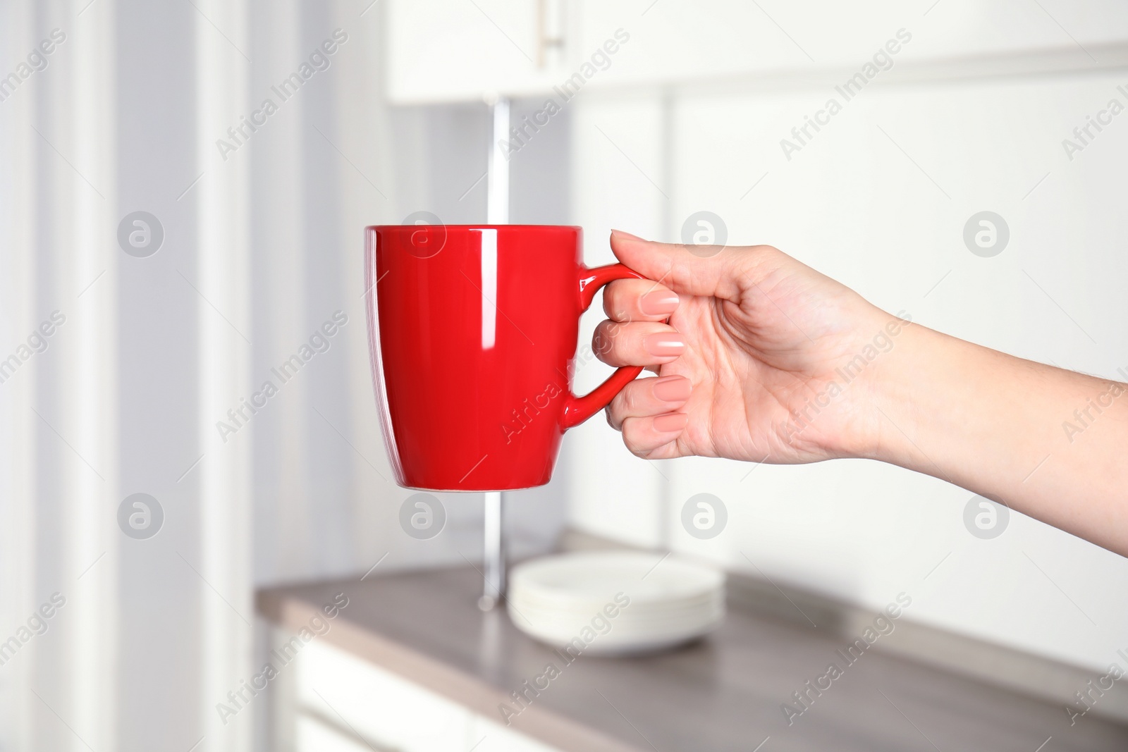 Photo of Woman holding red cup at home, closeup