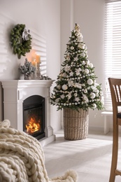 Photo of Beautiful Christmas tree and burning fireplace in living room interior