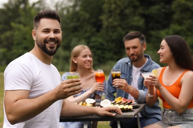 Photo of Friends having cocktail party outdoors. Happy man with glass of drink, selective focus