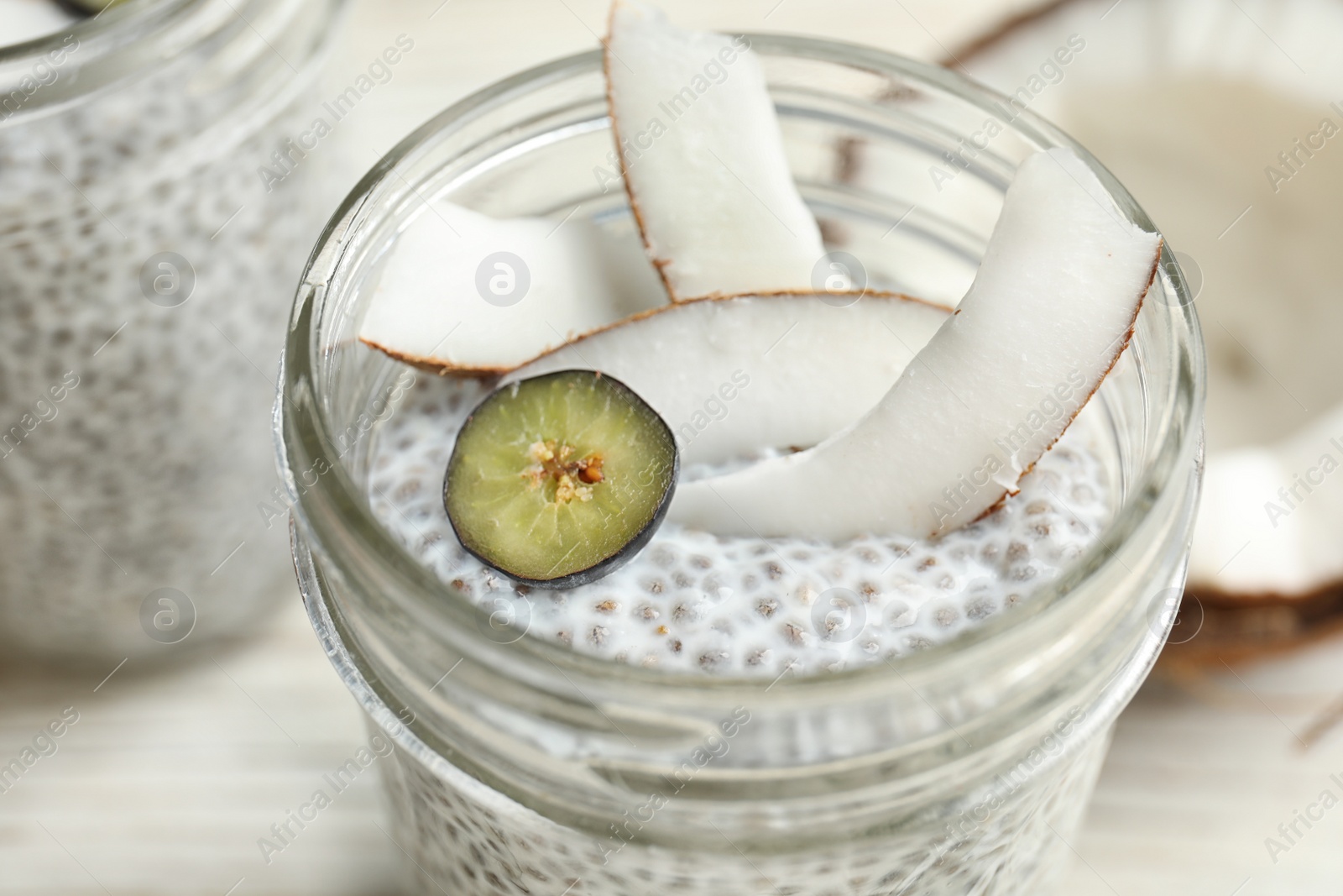 Photo of Jar of tasty chia seed pudding with coconut on table, closeup