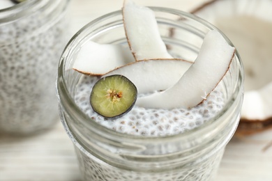 Jar of tasty chia seed pudding with coconut on table, closeup