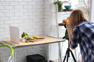 Young woman taking picture of lemons, mint and ginger in professional studio. Food photography