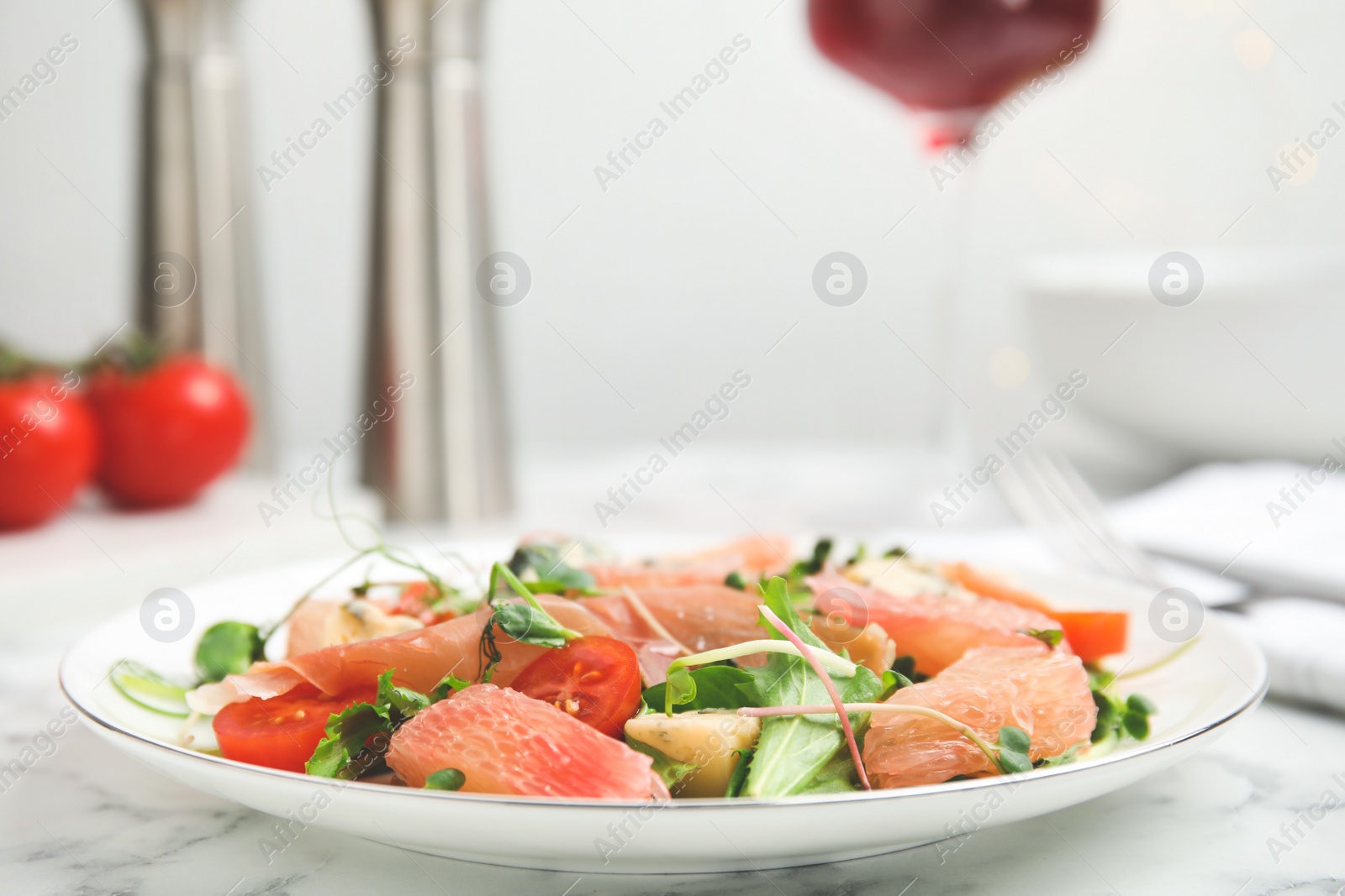 Photo of Delicious pomelo salad with prosciutto served on white marble table, space for text