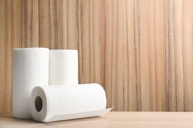 Photo of Rolls of paper tissues on wooden table. Space for text