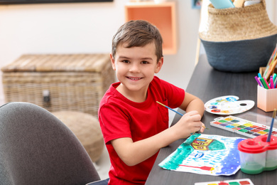 Little child painting at table in room