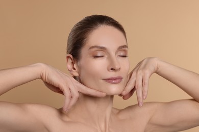 Photo of Woman massaging her face on beige background