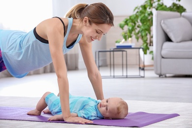 Young sportive woman doing exercise with her son at home. Fitness training