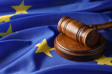 Photo of Wooden judge's gavel on flag of European Union, closeup. Space for text
