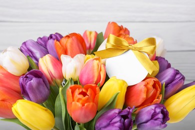 Bouquet of beautiful colorful tulips with blank card on white wooden background, closeup. Birthday celebration