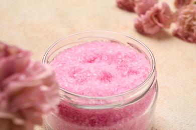 Aromatic sea salt and flowers on beige textured table, closeup