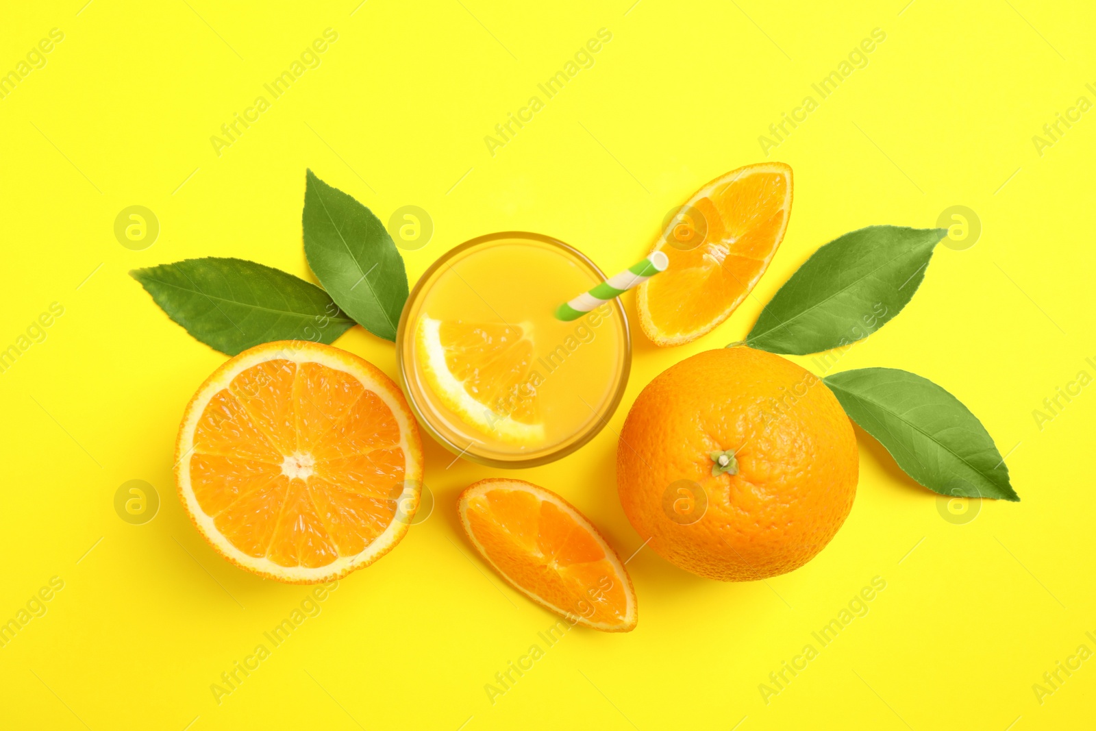 Photo of Glass of orange juice and fresh fruits on yellow background, flat lay