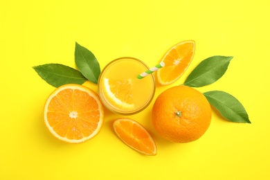 Glass of orange juice and fresh fruits on yellow background, flat lay