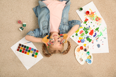 Cute little child with painted face and palms on floor, top view