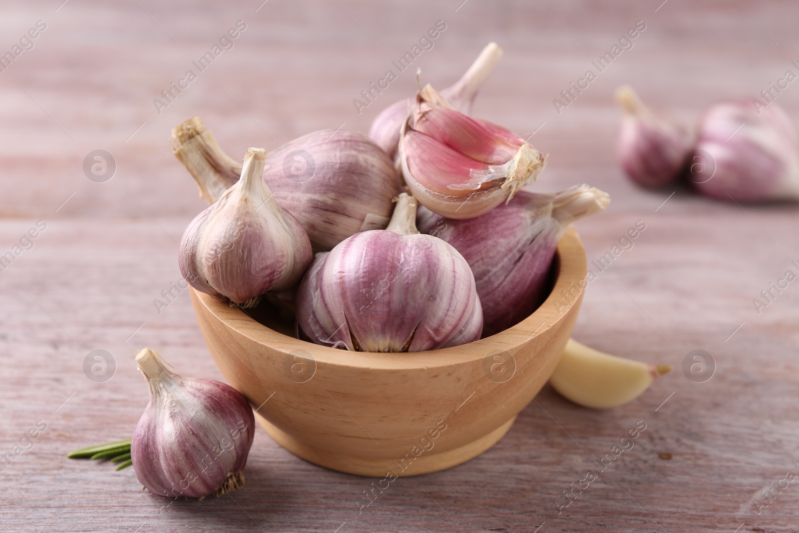 Photo of Bowl with fresh garlic on wooden table, closeup