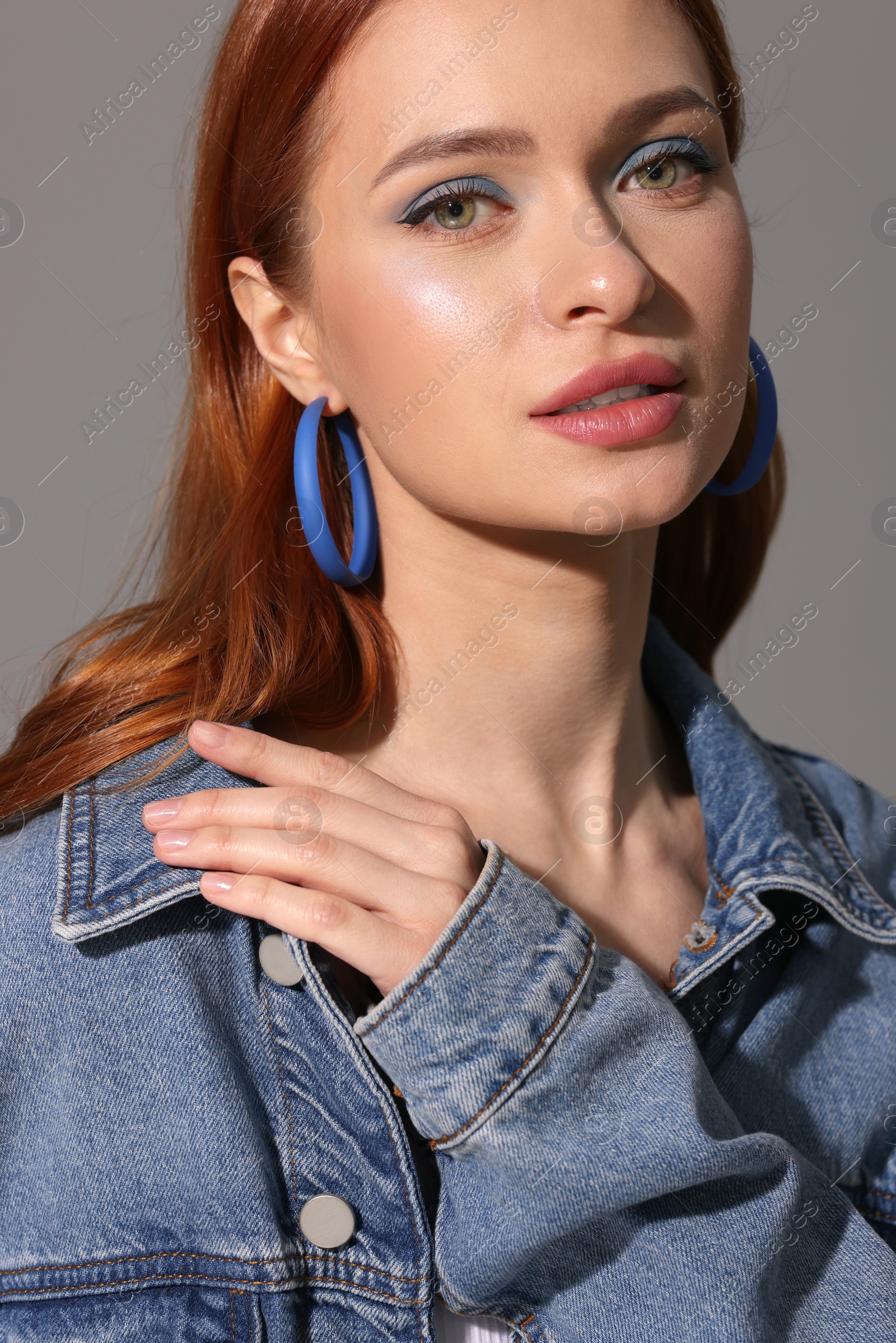 Photo of Beautiful young woman in denim jacket on gray background