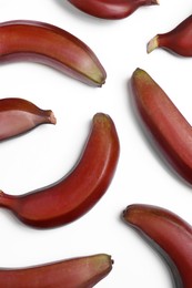 Tasty red baby bananas on white background, flat lay
