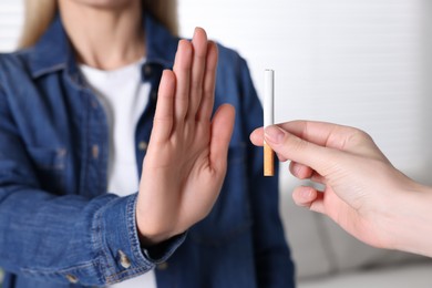 Photo of Woman refusing cigarette on light background, closeup. Quitting smoking concept