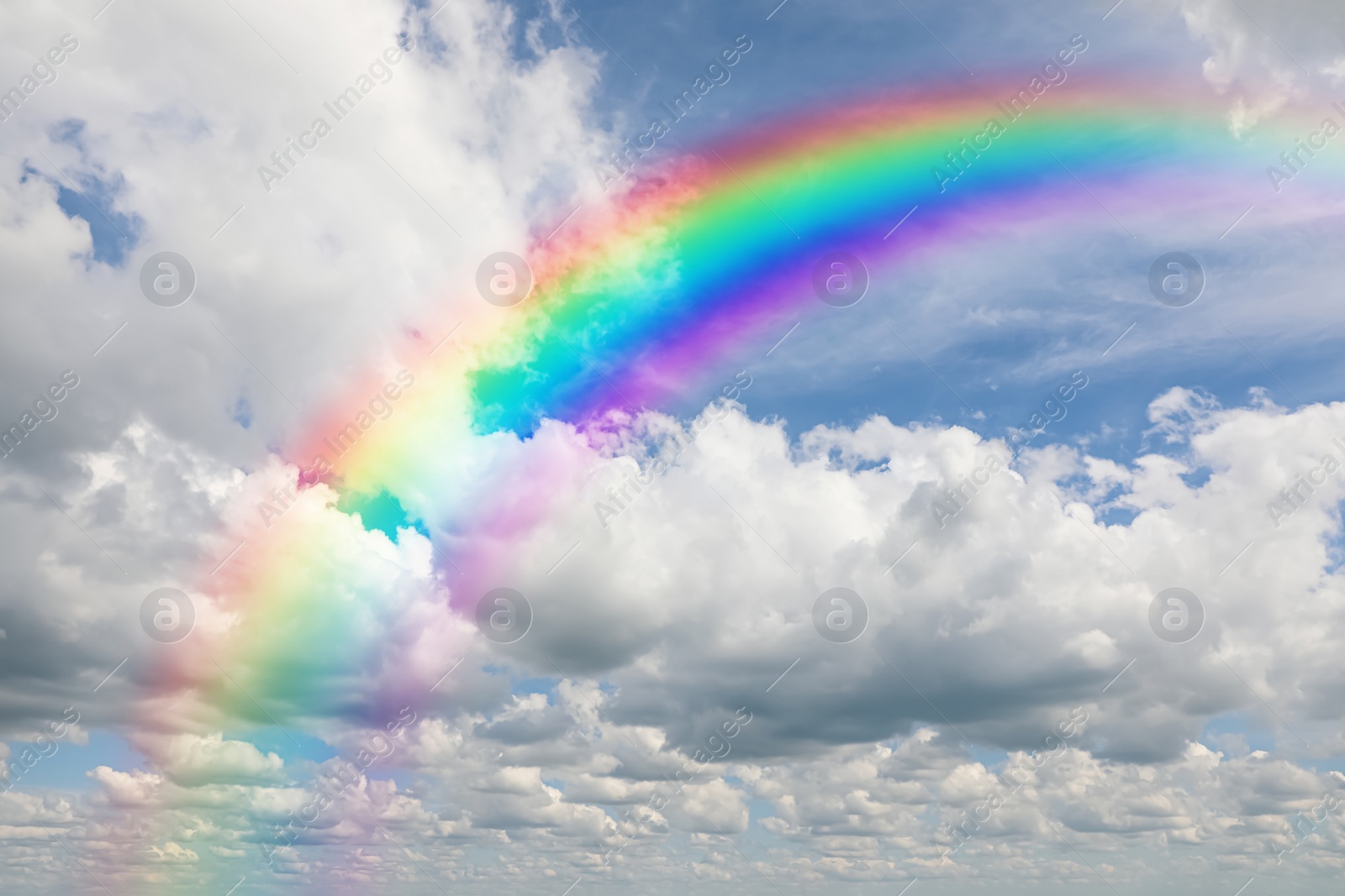 Image of Beautiful view of bright rainbow in blue sky on sunny day