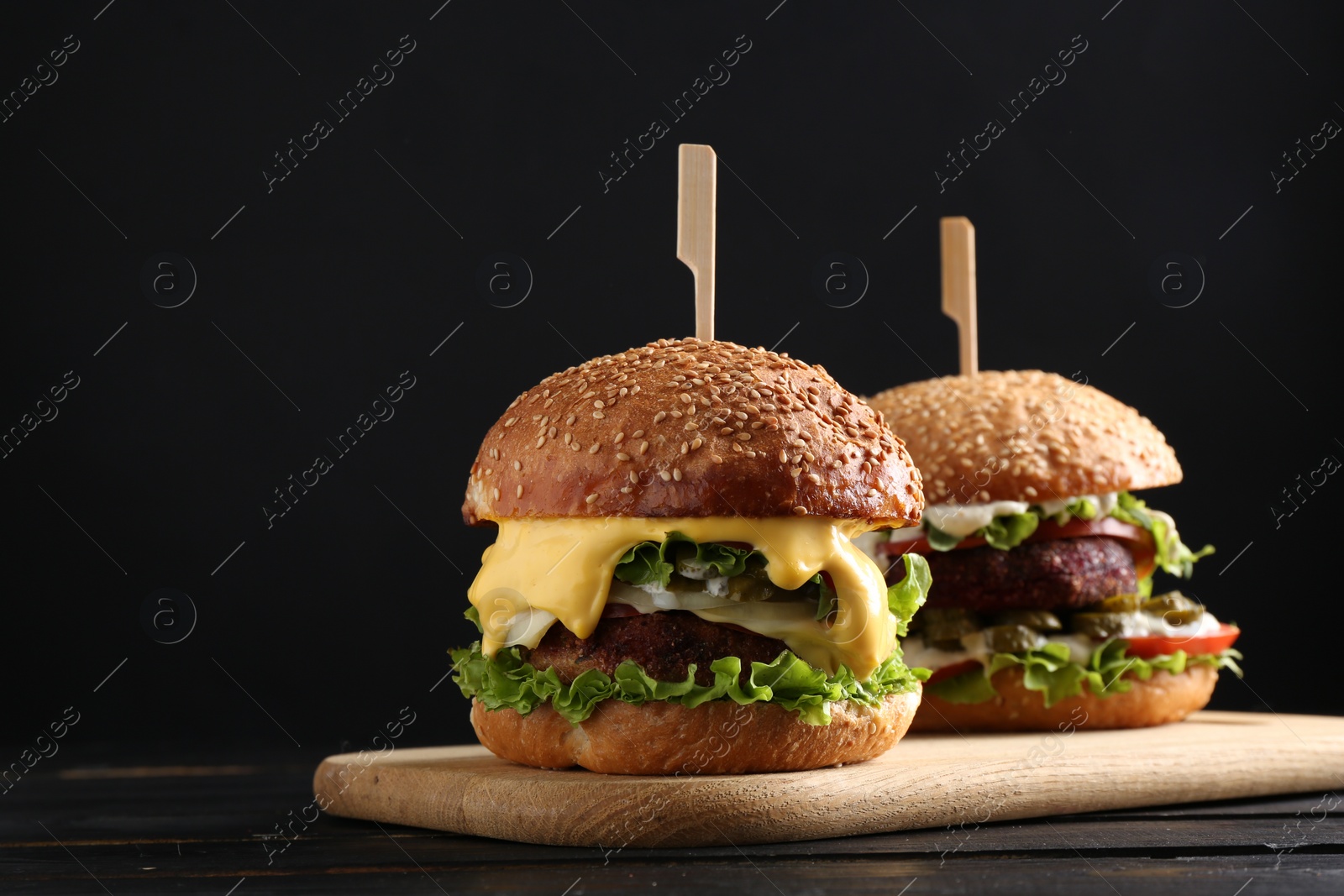 Photo of Vegetarian burgers with delicious patties on black wooden table