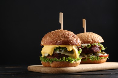 Photo of Vegetarian burgers with delicious patties on black wooden table