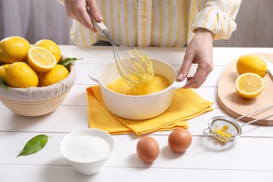 Woman cooking lemon curd at white wooden table, closeup