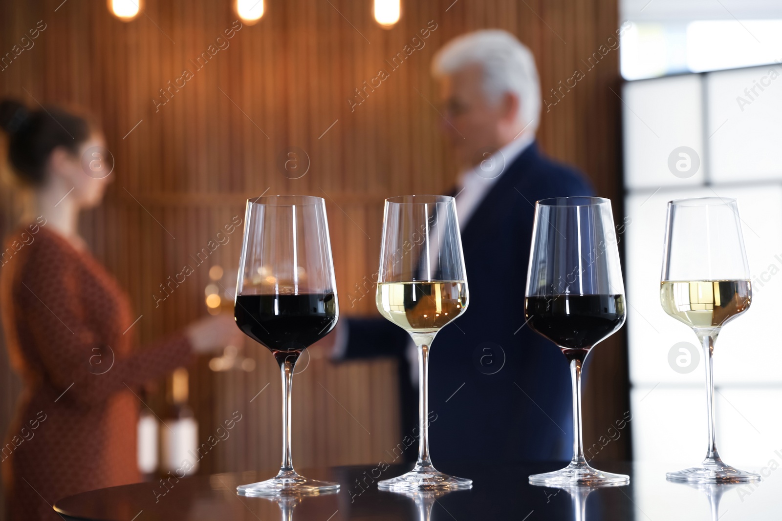 Photo of Glasses of different wines on table against blurred background