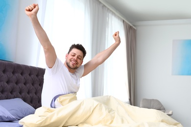 Handsome man stretching in morning, space for text. Bedtime