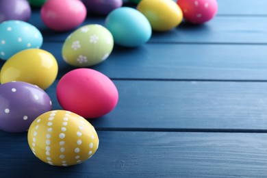 Photo of Colorful eggs on blue wooden background, space for text. Happy Easter