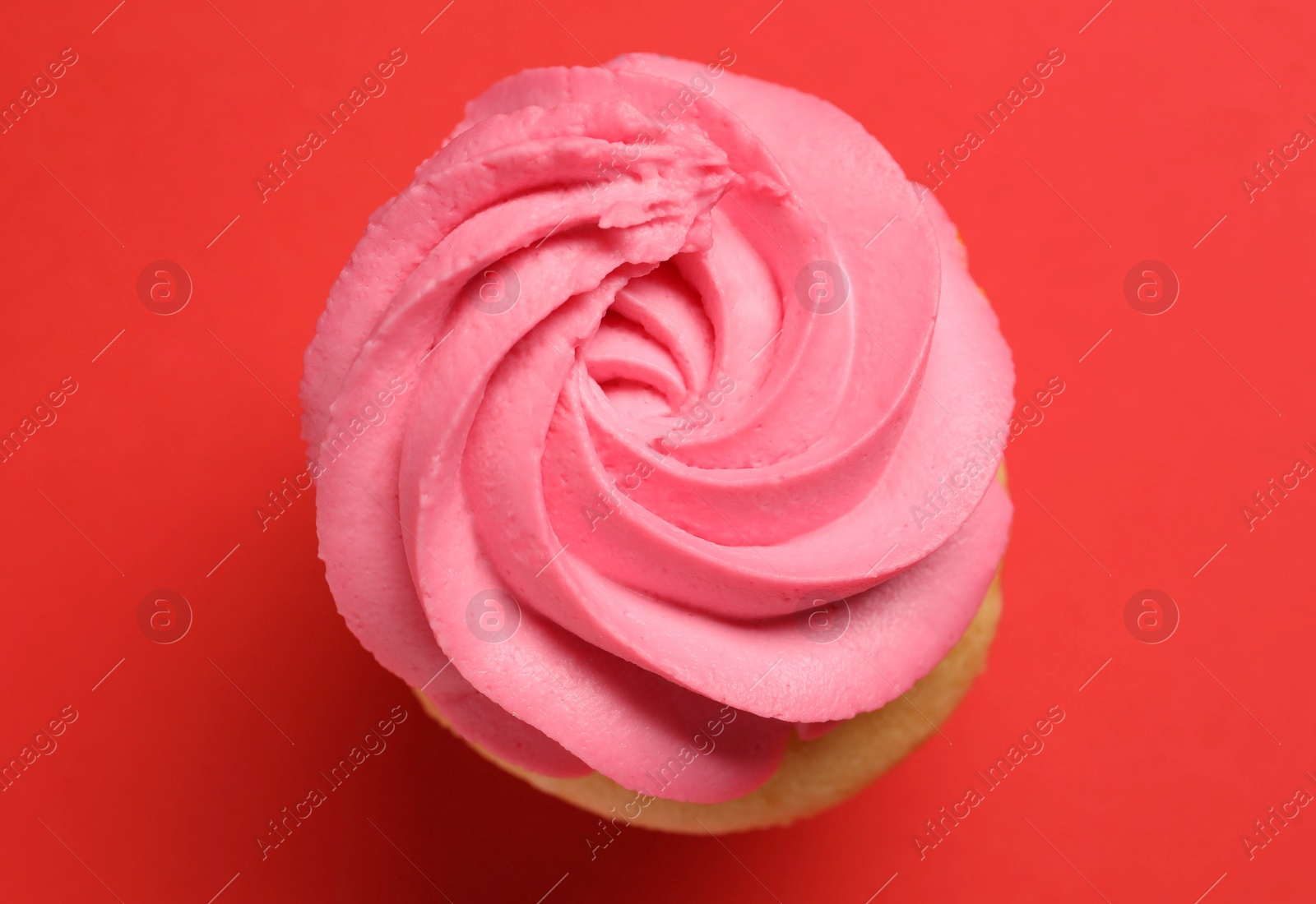 Photo of Delicious cupcake with bright cream on red background, top view