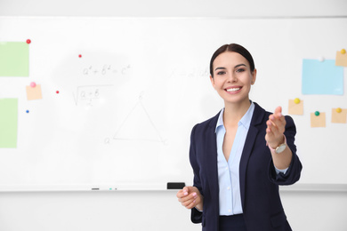 Photo of Young teacher near whiteboard in modern classroom. Space for text