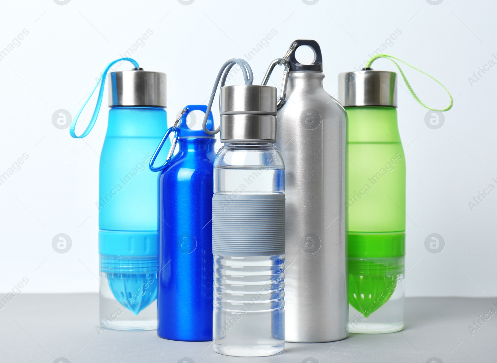 Photo of Five various sport bottles on table against white background