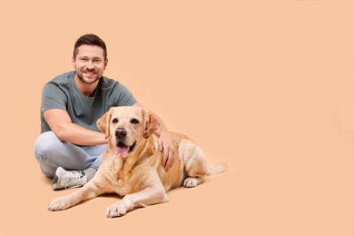 Photo of Man with adorable Labrador Retriever dog on beige background, space for text. Lovely pet