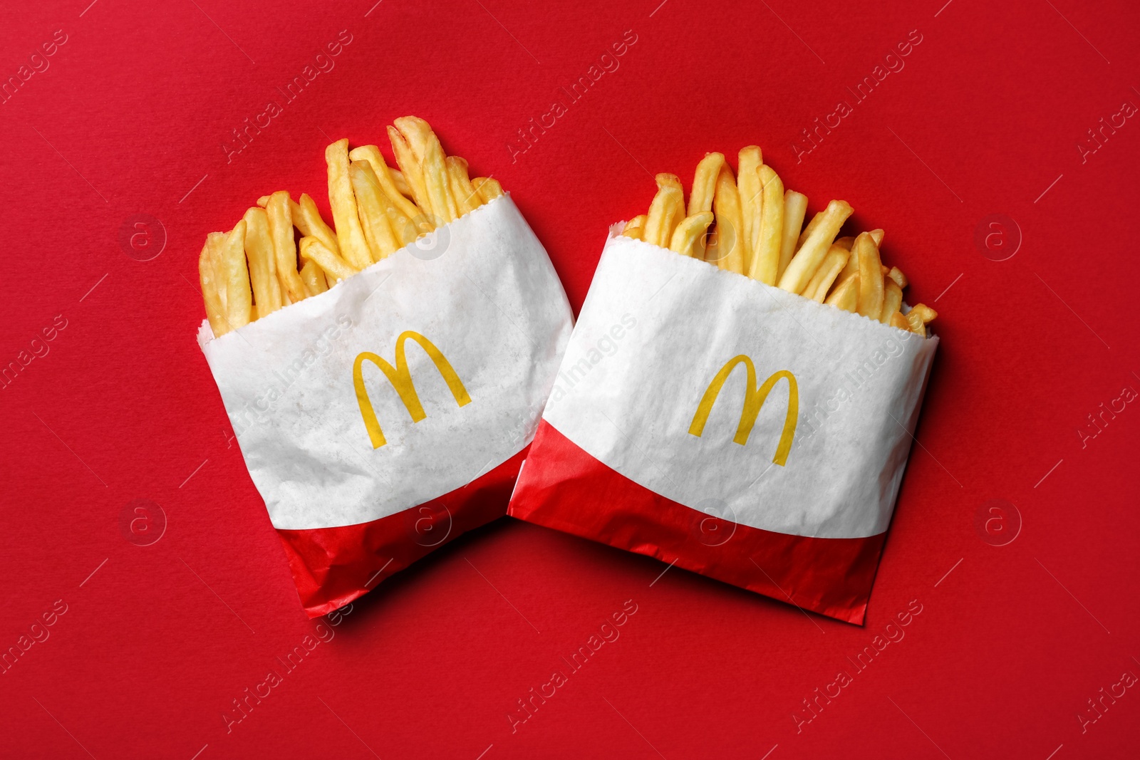 Photo of MYKOLAIV, UKRAINE - AUGUST 12, 2021: Two small portions of McDonald's French fries on red background, flat lay