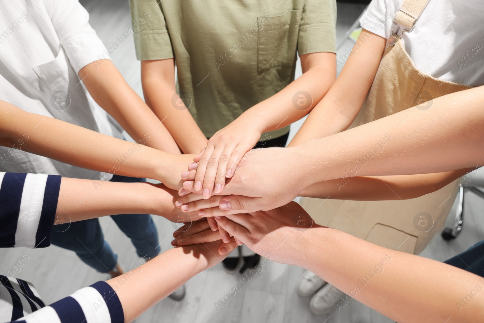 Photo of Group of people holding hands together indoors, closeup. Unity concept