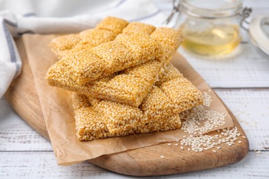 Photo of Delicious sesame kozinaki bars on white wooden table, closeup