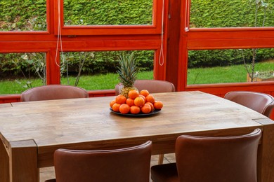 Photo of Wooden table with fruits and stylish chairs on terrace