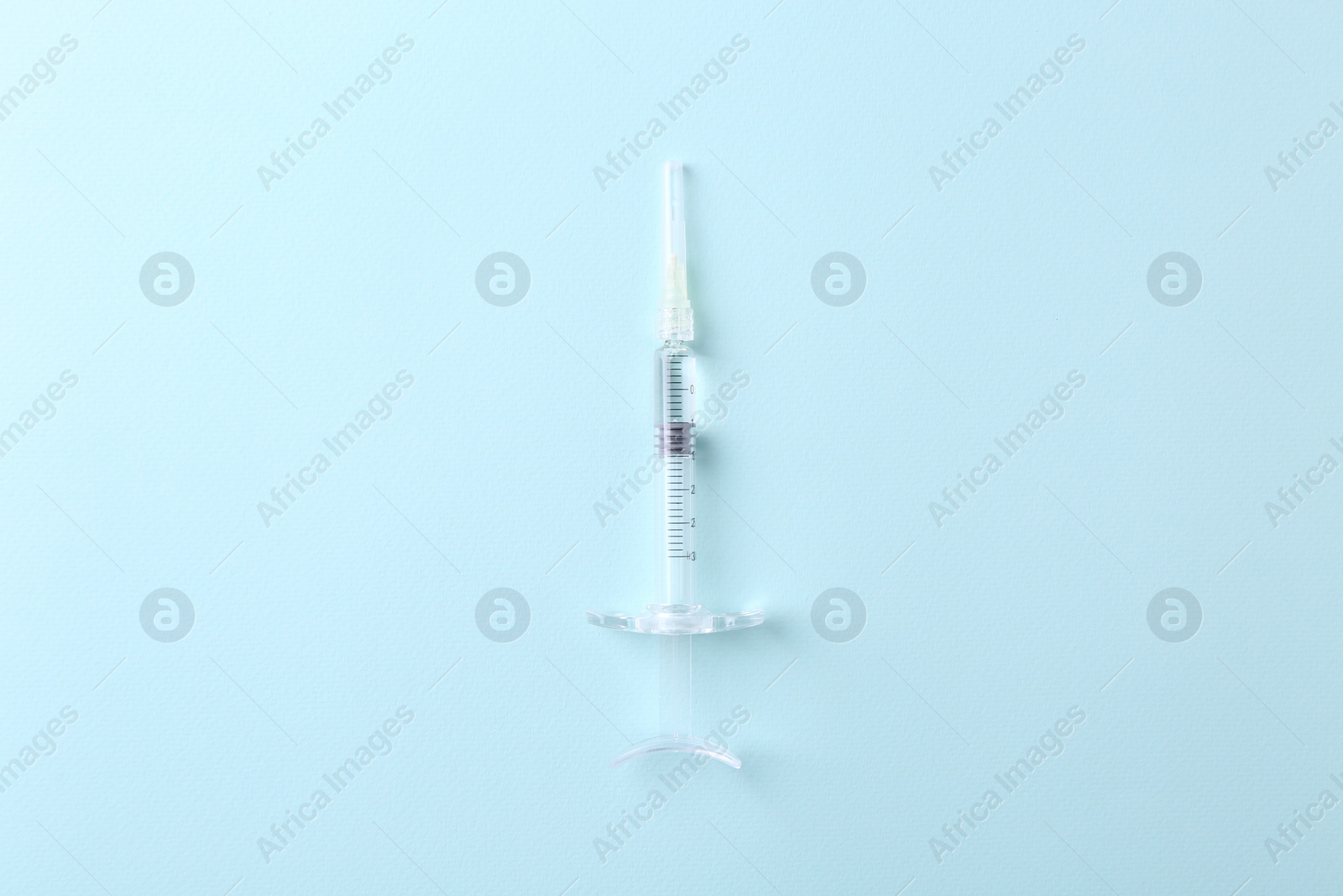 Photo of Cosmetology. Medical syringe on light blue background, top view