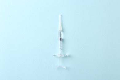 Photo of Cosmetology. Medical syringe on light blue background, top view