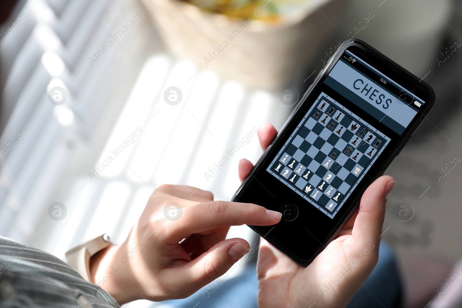 Image of Woman playing online chess on smartphone indoors, closeup