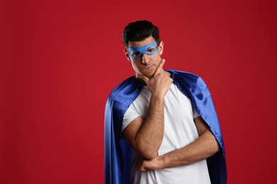 Photo of Man wearing superhero cape and mask on red background. Space for text