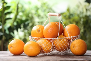 Photo of Basket and fresh oranges on wooden table. Space for text