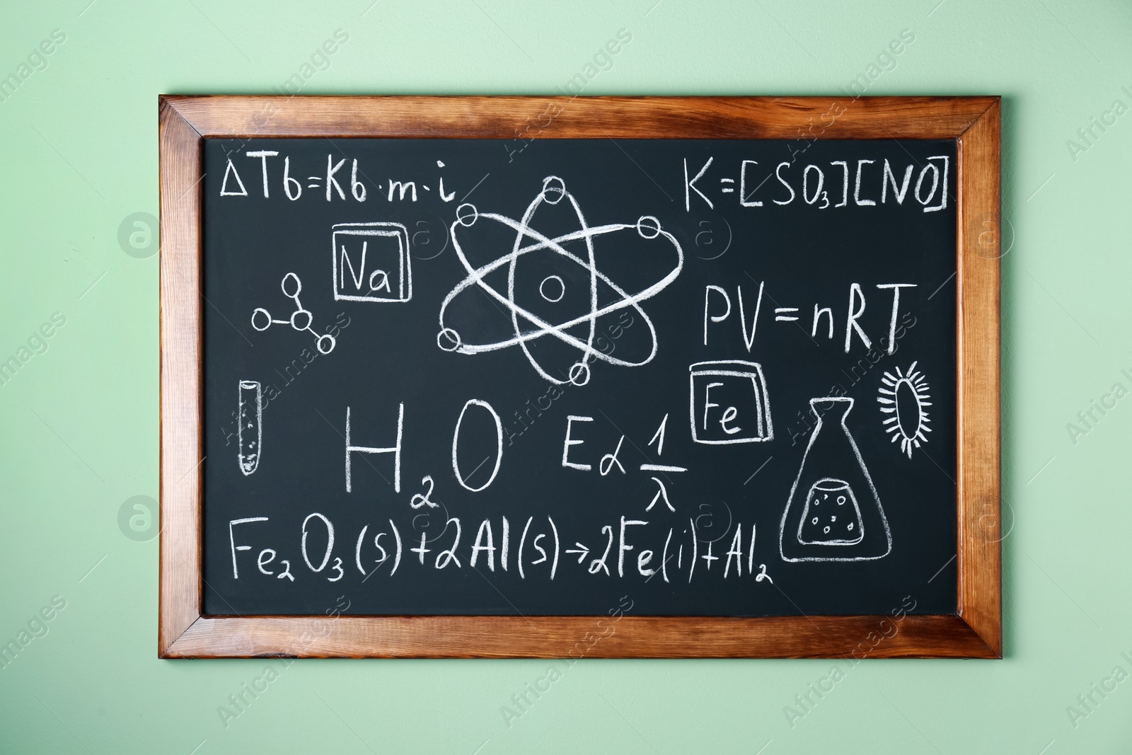 Photo of Blackboard with different chemical formulas written with chalk on light green wall