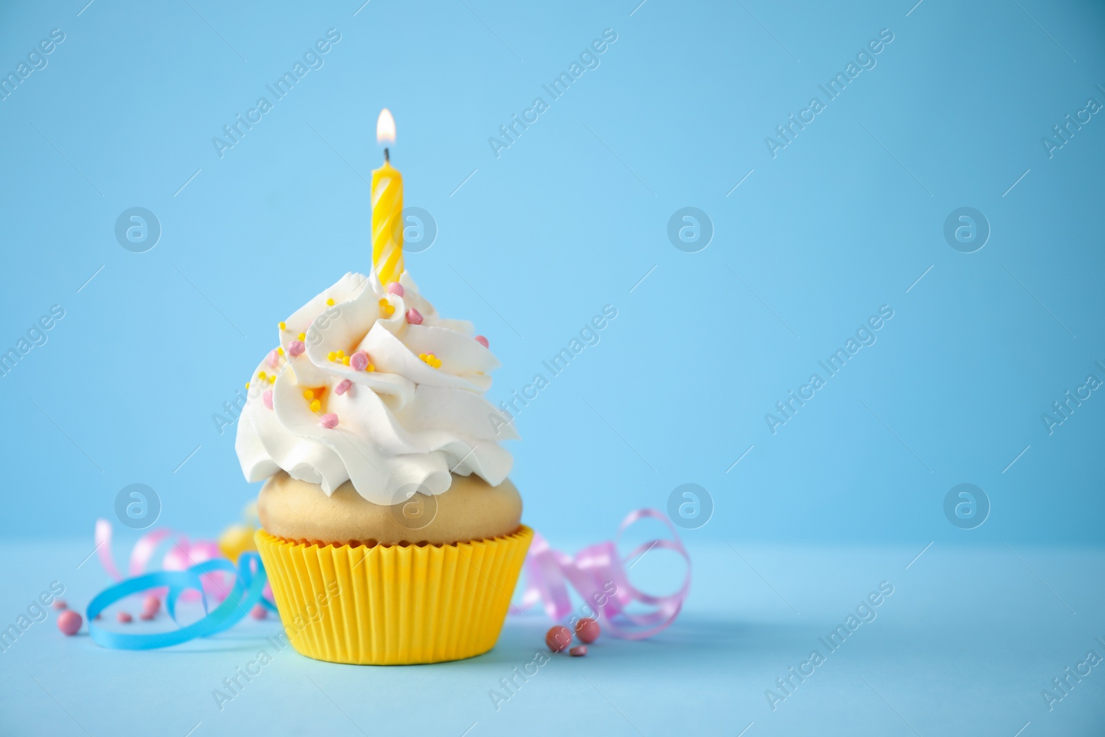 Photo of Delicious birthday cupcake with candle on light blue background. Space for text