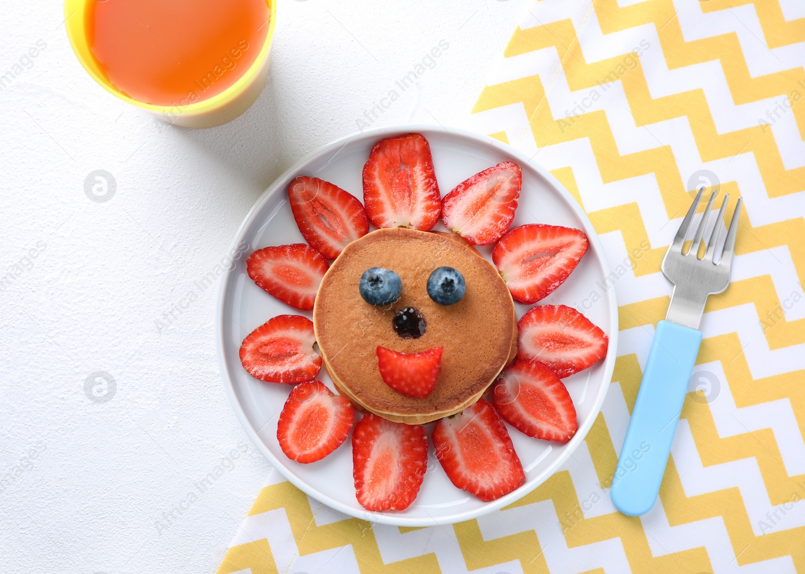 Photo of Tasty pancakes served with berries and juice on white table, flat lay. Creative idea for kids breakfast