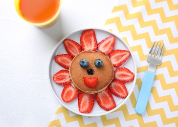 Photo of Tasty pancakes served with berries and juice on white table, flat lay. Creative idea for kids breakfast