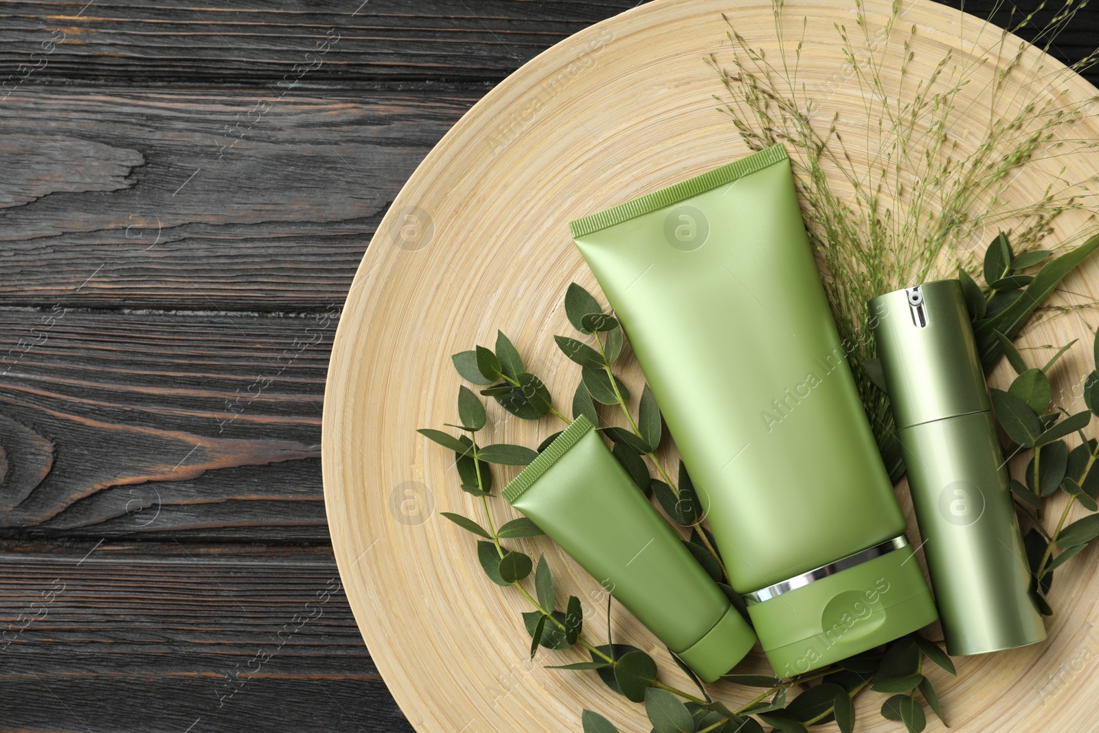 Photo of Set of cosmetic products and plants on dark wooden table, top view