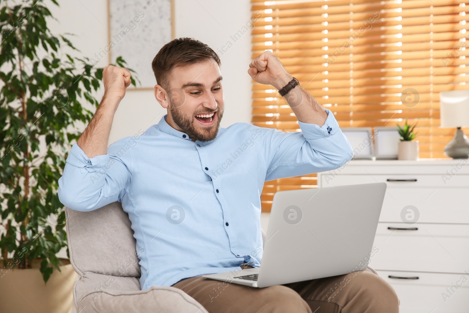 Photo of Emotional man participating in online auction using laptop at home