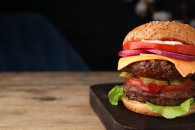 Photo of Tasty cheeseburger with patties on wooden table, closeup. Space for text