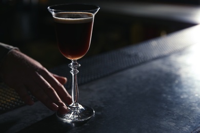 Photo of Barman serving espresso martini cocktail at counter, closeup. Space for text
