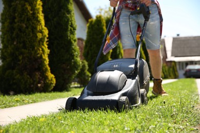 Man cutting green grass with lawn mower on backyard, closeup